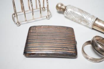 A French white metal cigarette case, a silver toast rack, a French white metal mounted glass scent bottle and a pair of French white metal napkin rings.